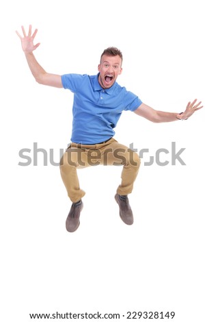 casual young man jumping in the air and screaming with his arms wide open. on white background