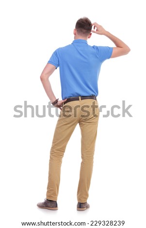 full length back view picture of a young casual man thinking while holding a hand on his waist and scratching his head with the other. isolated on a white background