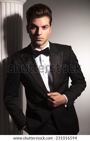 Portrait of a young elegant business man fixing his jacket while looking at the camera.