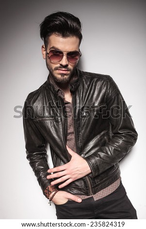 Handsome fashion man posing with his hand in pocket, on studio background.