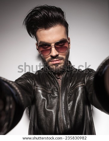 Close up picture of a handsome fashion man holding the camera with his hands.