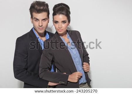 Handsome young fashion man holding his lover from behind while looking at the camera.