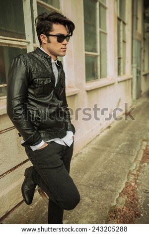 Attractive young fashion man holding both hands in pockets, leaning on a ladder.