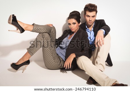 Handsome young casual man sitting on the floor while his girlfriend is leaning on him.