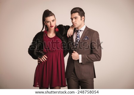 Fashion woman holding her arm on her lovers shoulder while he is fixing his jacket.