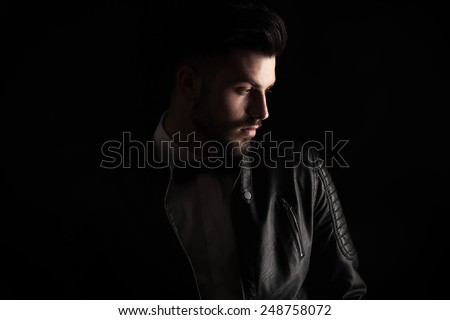 Attractive business man looking down to his side on dark studio background.