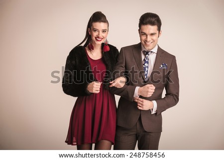 Happy elegant woman holding her man by the arm, both laughing at the camera.