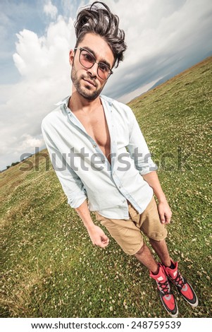Full body picture of a young fashion man posing outdoor, making a funny face.