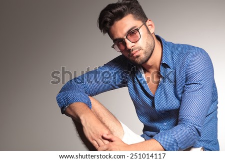 Portrait of a attractive young fashion man resting his hand on his knee while looking at the camera.