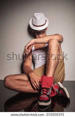 Casual young man resting on the floor with his hat on his face.