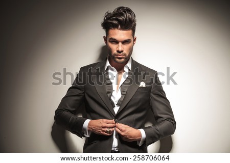 Handsome elegant business man looking at the camera while unbuttoning his jacket.