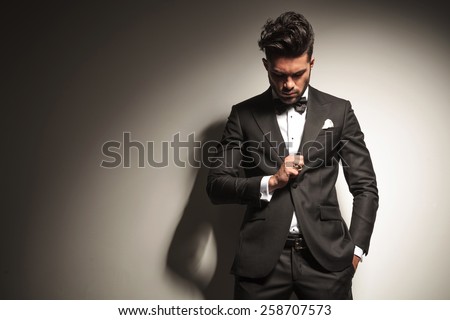 Handsome young business man looking down to his ring while holding one hand in his pocket.