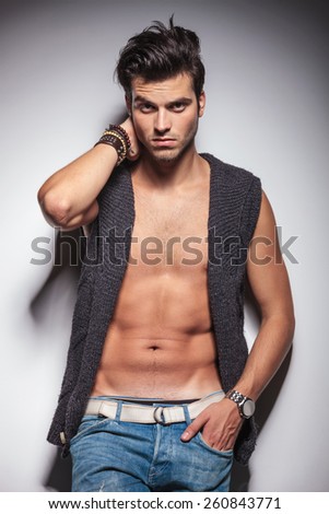 Hot casual man posing with one hand in his pocket while leaning on a wall.