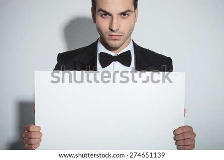 Portrait of a handsome business man holding a white board while looking at the camera.