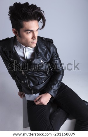 Attractive young fashion man relaxing on a white table while looking way from the camera.