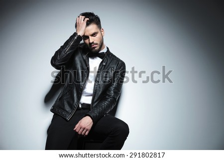 Picture of a handsome business man fixing his hair while sitting on a stool.