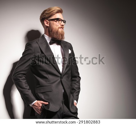 Side view picture of a happy young business man holding both hands in pockets while looking away from the camera.