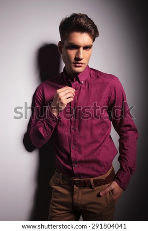Young attractive man holding his hand in pocket while fixing his collar.