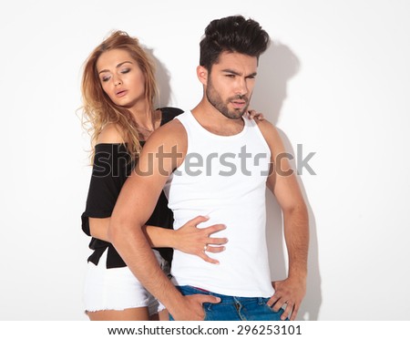 Side view of a young casual couple posing on white studio background.