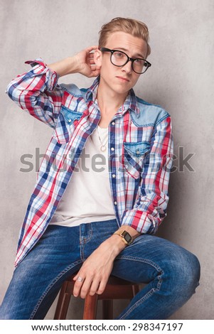 Casual young man sitting on a chair while scratching his head.