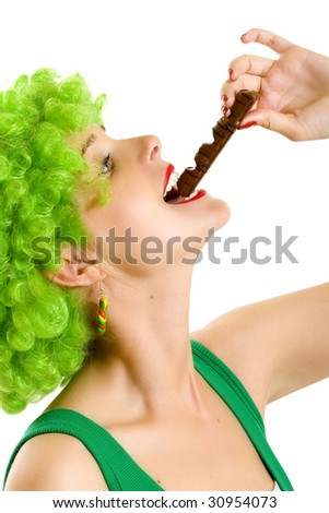 closeup of an attractive woman with green wig biting a chocolate bar