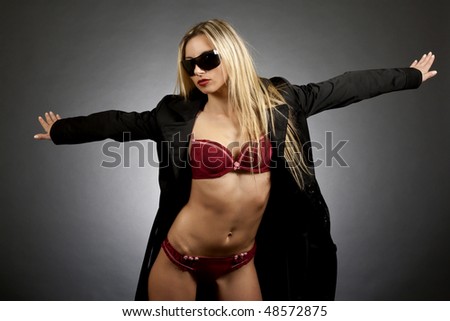 sexy blond woman wearing raincoat and sunglasses standing with arms wide open