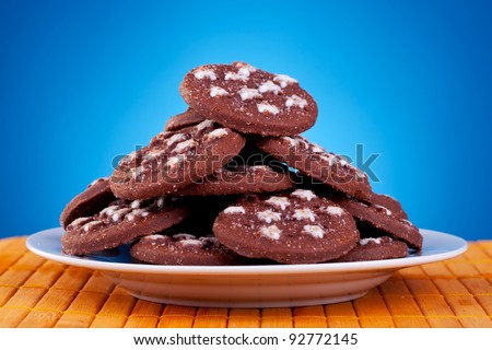 big pile of brown cookies on plate against blue background