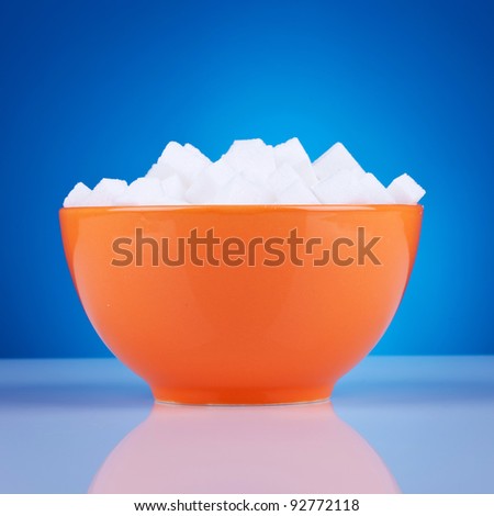 orange bowl of sugar cubes on a blue background