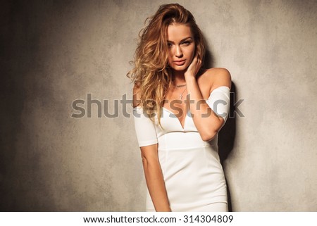 Potrait of a sexy elegant woman looking to the camera while holding one hand to the neck.