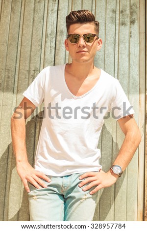 relaxed man resting his hands on his waist pose looking at the camera wearing sunglasses