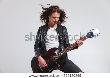 passionate woman guitarist with flying hair playing rock and roll music on her electric guitar