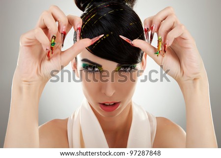 Closeup portrait of a serious lady with colorful eye makeup showing her big nails