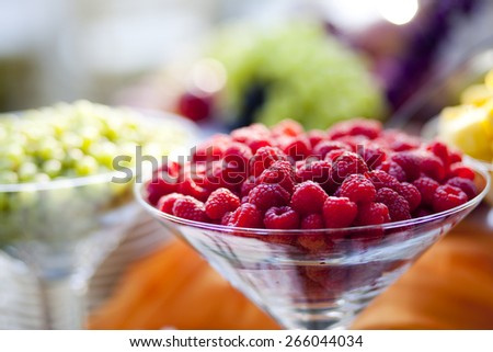 A closeup of a bowl of raspberries on an outdoor table