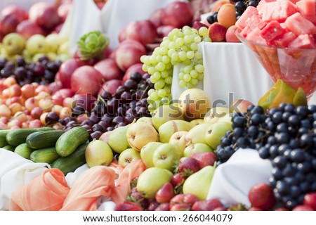Pears on an outdoor table of fruit including grapes, watermelon, cherries, apples, and strawberries