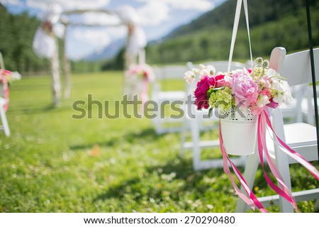 Happy outdoor Wedding Ceremony Scene for a summer mountain wedding. Wedding aisle, decorated wedding alter and flower decorations with mountains in the background.