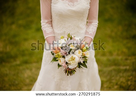 Bride holding wedding bouquet with Peonies, Tulips, Parrot Tulips, Roses, Dusty Miller, and Astilbe