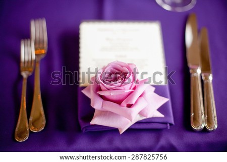 Rose at a formal dinner against a purple table cloth