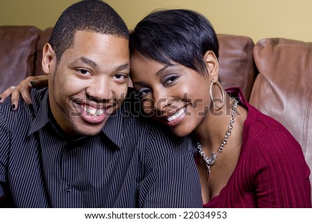stock photo : A happy couple on the couch and the woman has her arm around the man