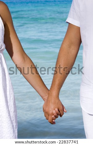 A Couple Holding Hands On The Beach. of a couple holding hands