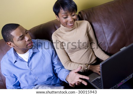 a happy couple reads the paper and browses the internet together