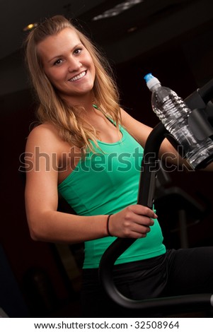 An athletic girl does cardio on a step machine at the gym