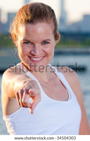 an athletic woman points at the camera