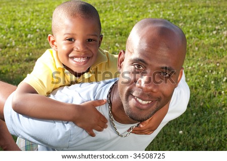 a happy dad poses with his son, focus is on the son