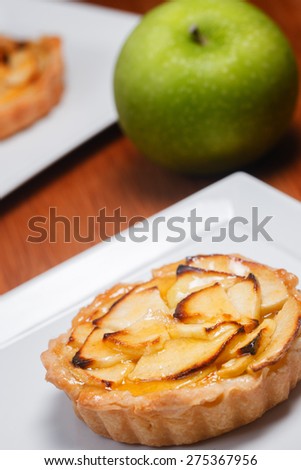 Fresh apple tart on a square white plate with a granny smith apple in the background.