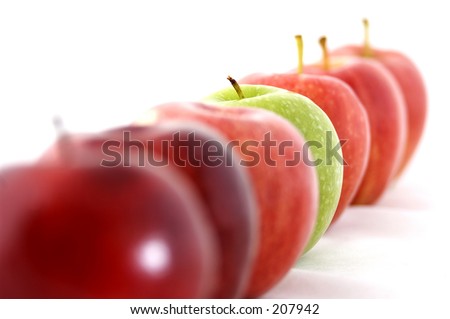 A green apple is the odd one out in a line of red