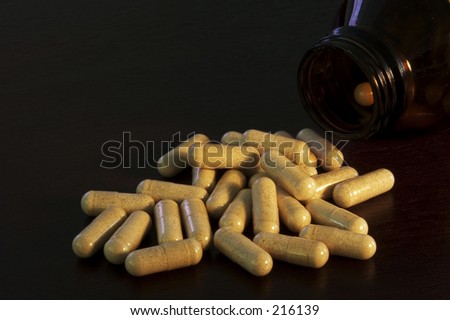 Pills spill from a bottle onto a wooden table