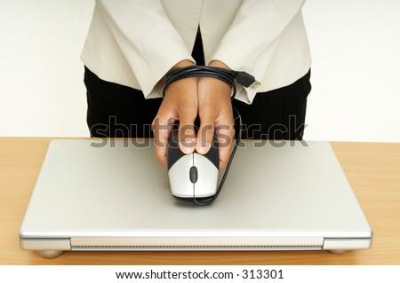 A woman holds a mouse over a laptop computer, her hands are tied up by the mouse cable