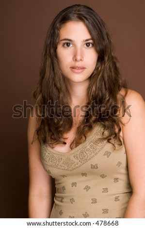 A naturally beautiful young woman in a patterned top on a brown backdrop