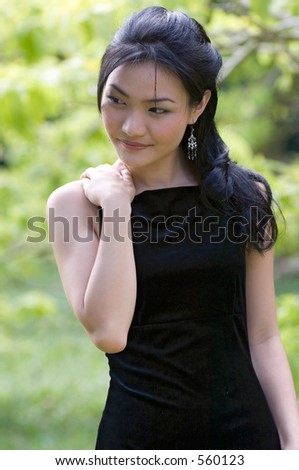 A beautiful asian model in a black evening dress posing outdoors