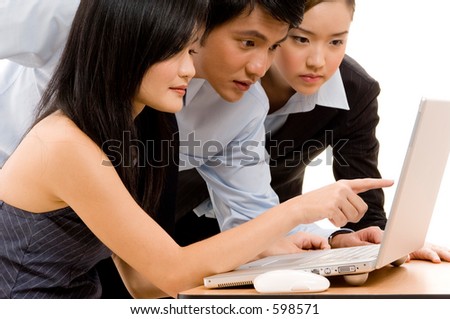 A chinese businesswoman points something out to her colleagues on a laptop computer